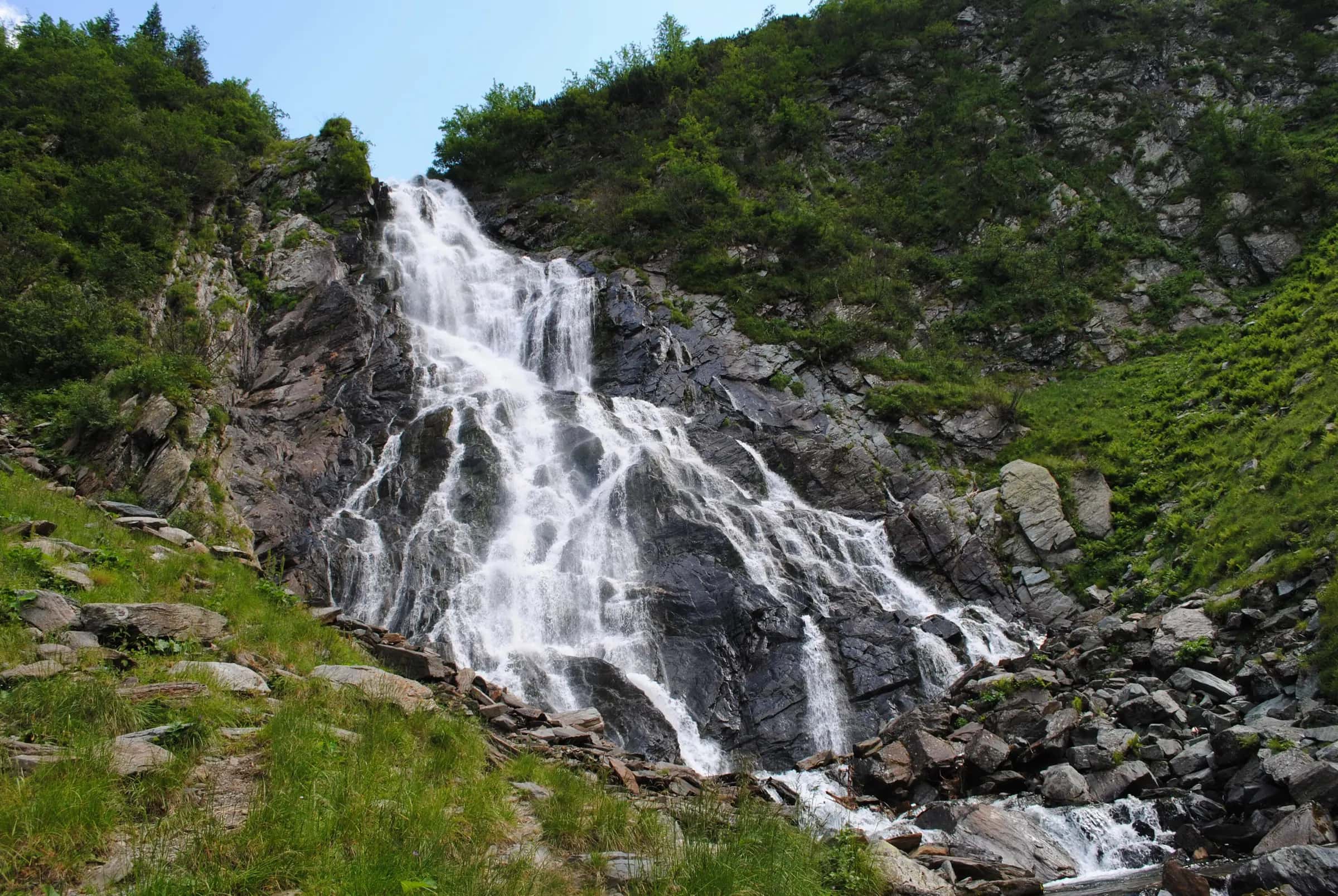 Bâlea Waterfall pouring down the rocks in a green valley