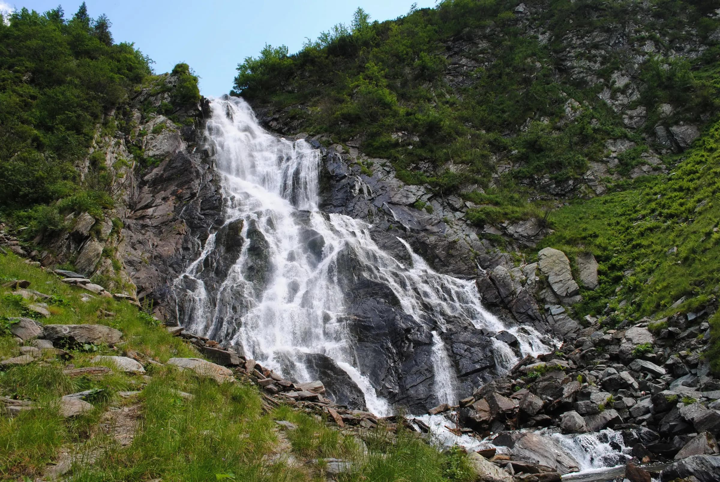 Bâlea Waterfall pouring down the rocks in a green valley