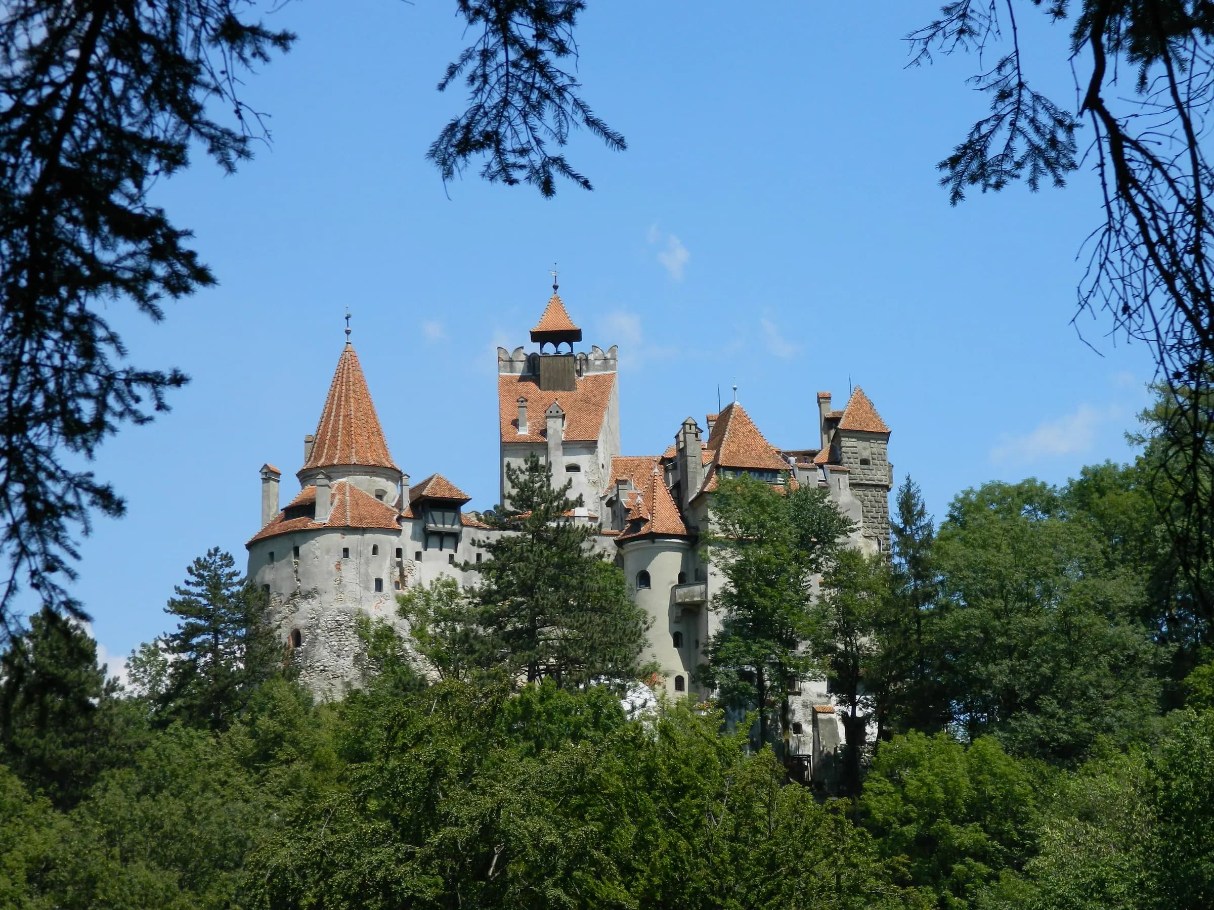 Bran Castle rising above the forest under a blue sky