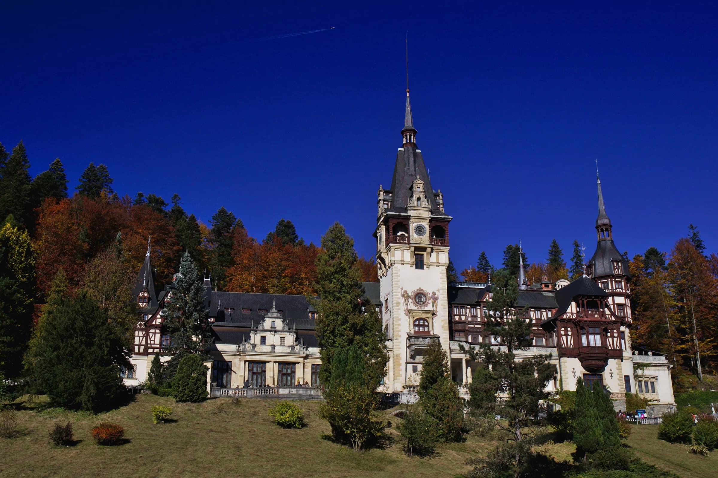 Peleș Castle with its clock tower under a dark blue sky