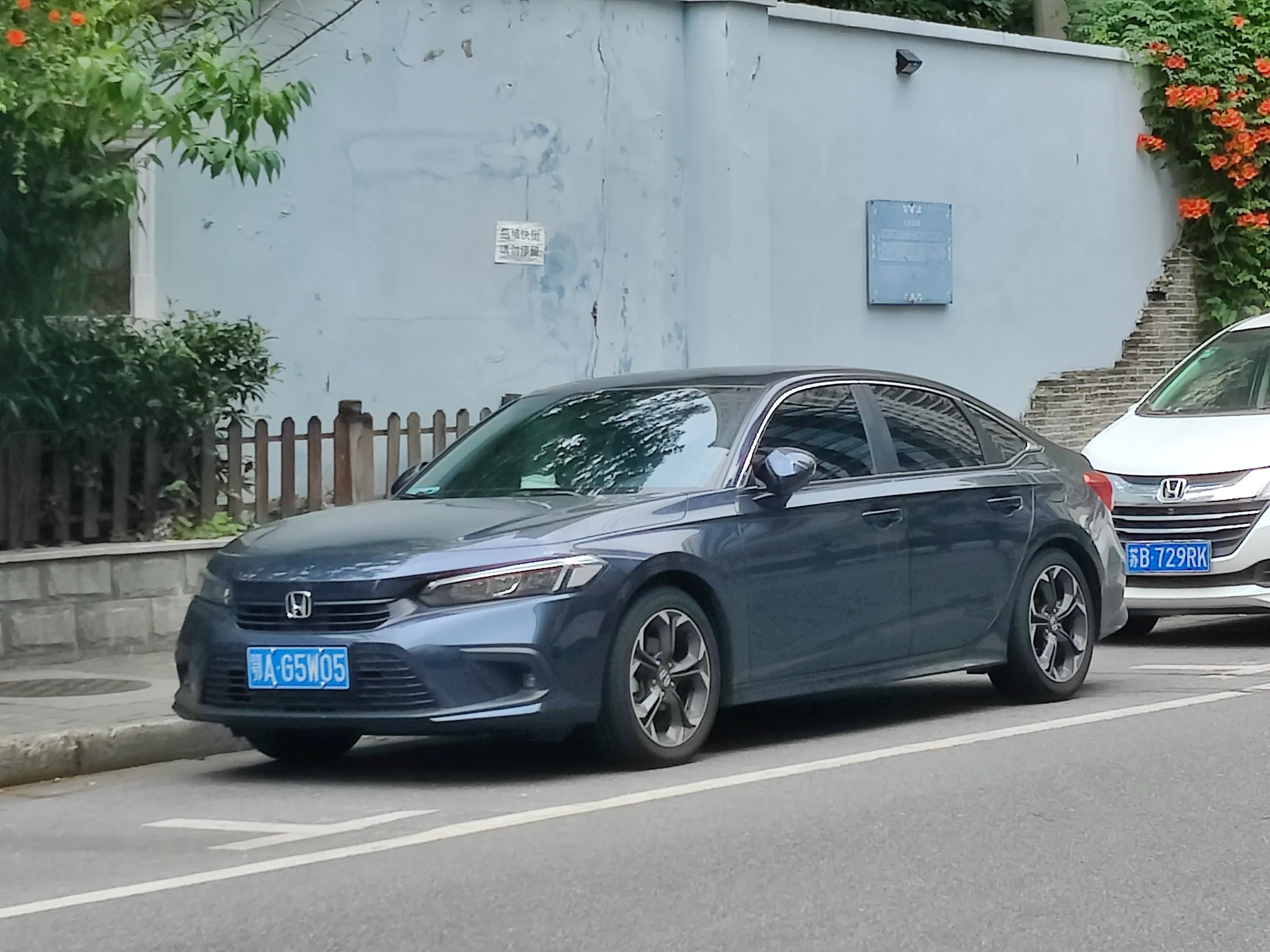 Una Honda Civic berlina grigio-azzurra parcheggiata lungo il marciapiede