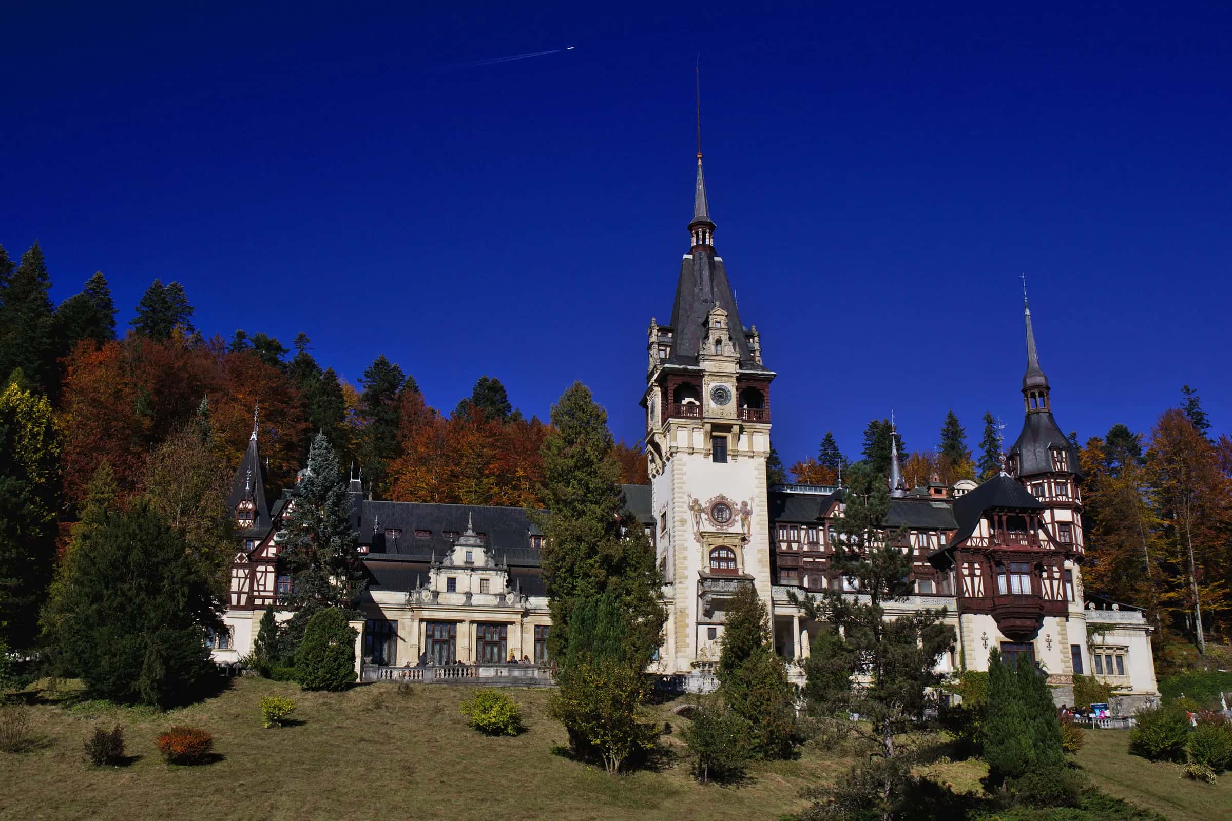 Peleș Castle with its clock tower under a dark blue sky